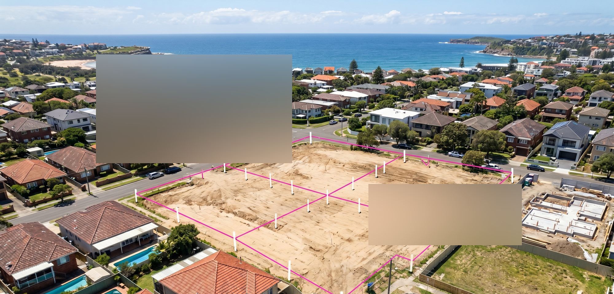 Aerial view of a cleared residential development site in coastal NSW, surveyor stakes visible across the block, suburb and ocean headland behind